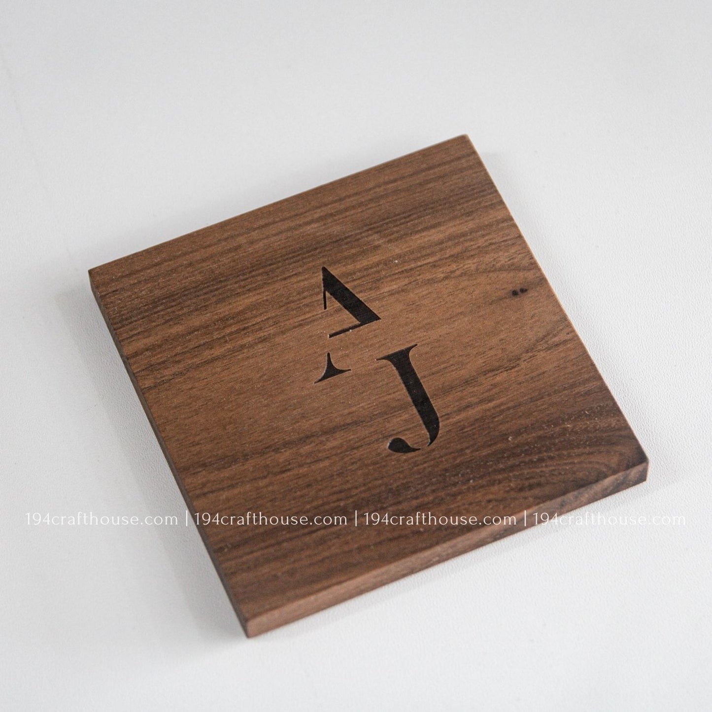 Wooden coaster with engraved initials on a white background