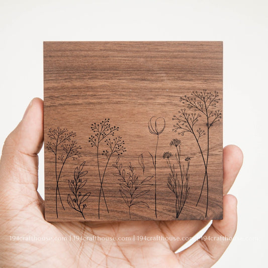 Wooden coaster with engraved floral designs held in a hand against a white background