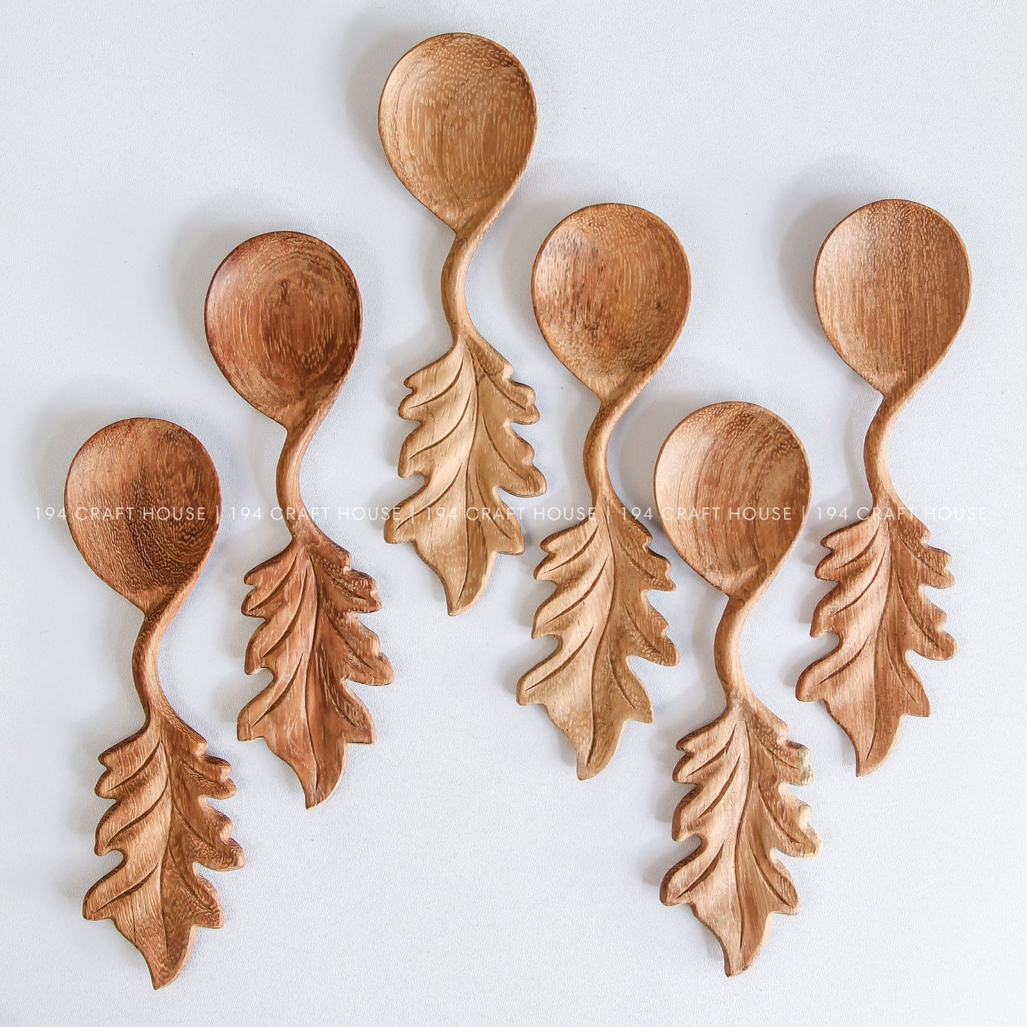 Collection of handcrafted wooden spoons with decorative leaf-shaped handles and unique natural wood grain