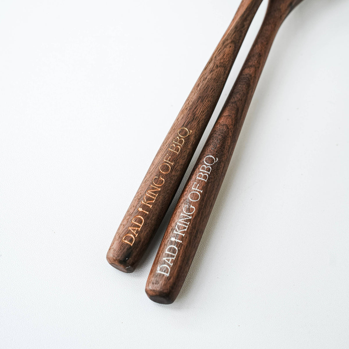 Two walnut spoon handles arranged side by side with matching BBQ engravings