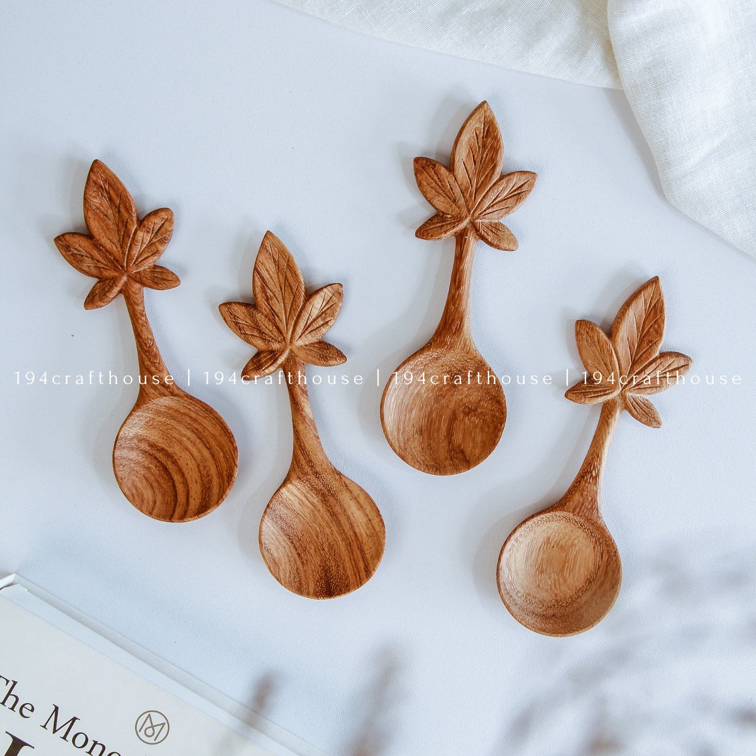 Set of four wooden spoons with leaf designs on a white background