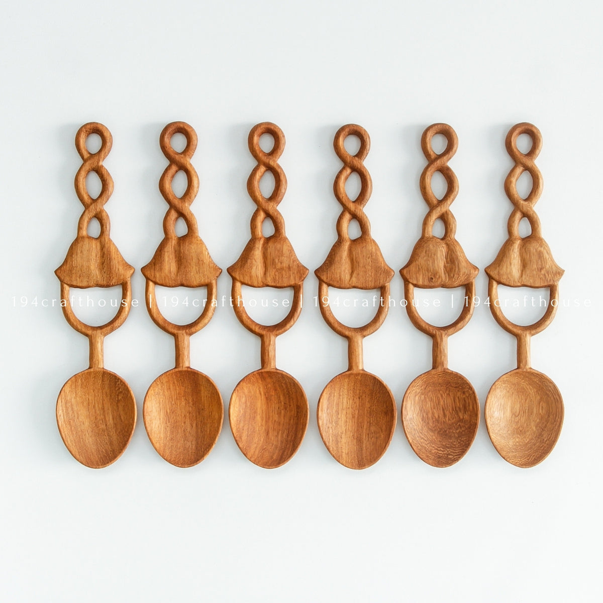 Six Doussie wood spoons in a row on a pale background, showing natural wood color and grain variation.