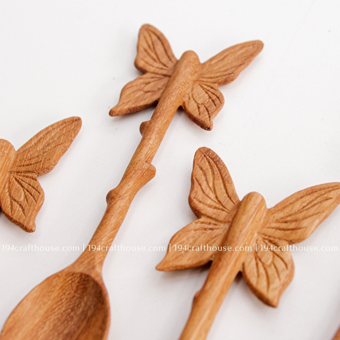 Hand-carved Butterfly wooden spoons crafted from doussie wood, featuring a sculpted butterfly handle on a white background.