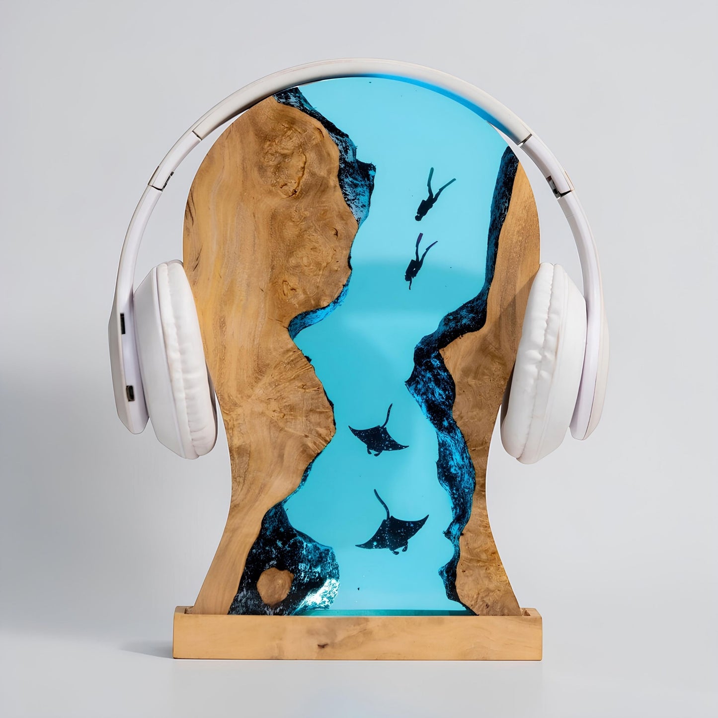 Handmade resin manta ray LED headphone stand holding over-ear headphones on a desktop with ambient LED lighting, lifestyle view