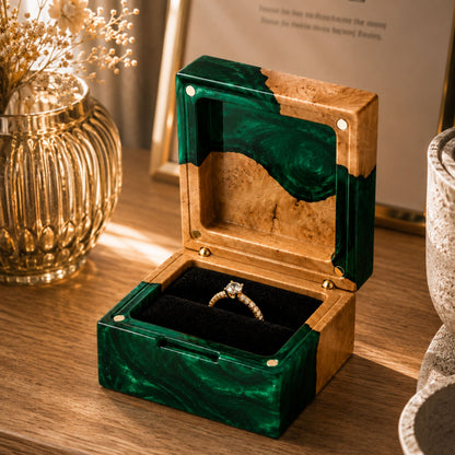 Open green resin and natural burl wood engagement ring box holding a diamond ring on a rustic wooden table.