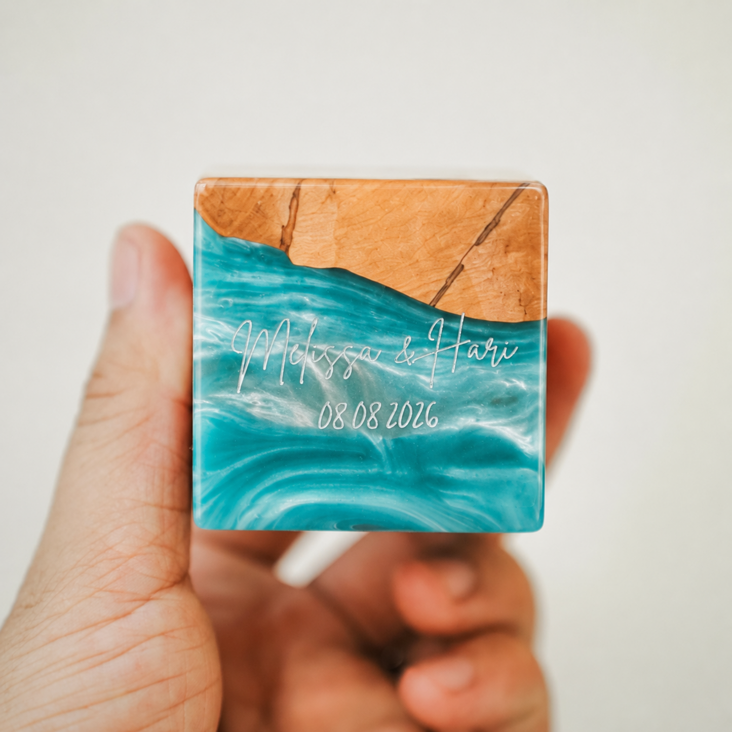 Custom engraved artisan ring box made of turquoise epoxy resin and wood, showcasing a personalized name and date engraving