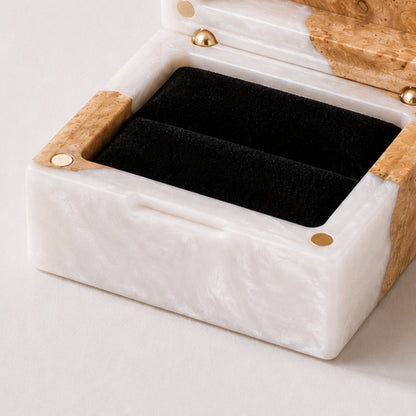 Close-up of an open square ring box made of pearl resin and burl wood with a black velvet interior and magnet closure.