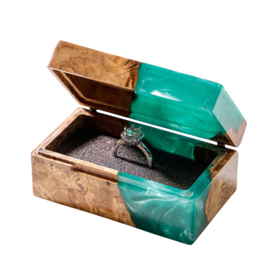 Open handcrafted wood and turquoise epoxy resin engagement ring box displaying a proposal diamond ring inside a black velvet slot.
