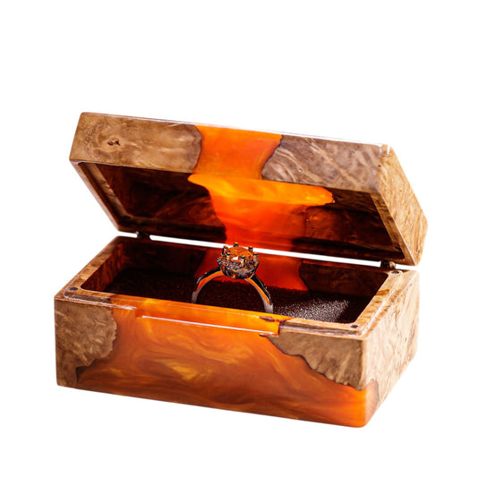 Open handcrafted wood and orange epoxy resin engagement ring box displaying a proposal diamond ring inside a black velvet slot.
