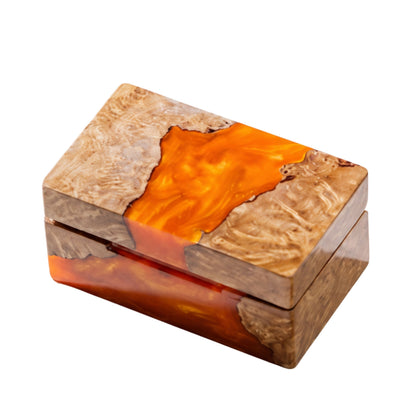 Top view of a closed rectangular ring box made from natural burl wood and swirled orange epoxy resin.
