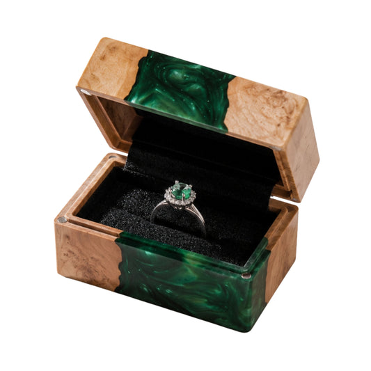 Open handcrafted wood and emerald green epoxy resin engagement ring box displaying a proposal diamond ring inside a black velvet slot.
