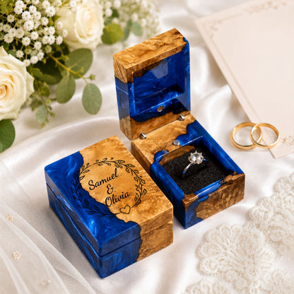 Personalized wooden and blue resin ring box engraved with couple names for a wedding proposal.