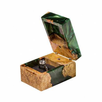 Open green epoxy resin and natural burl wood ring box holding a diamond engagement ring in a black foam slot.