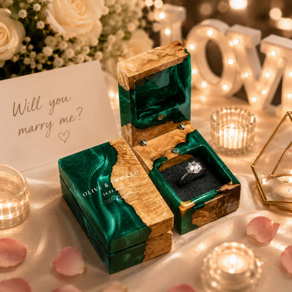 Personalized green resin and wood ring box engraved with couple names and wedding date set in a romantic proposal scene.