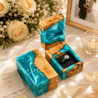 Personalized turquoise resin and wood ring box engraved with couple names and wedding date set in a romantic proposal scene with white roses and candles.