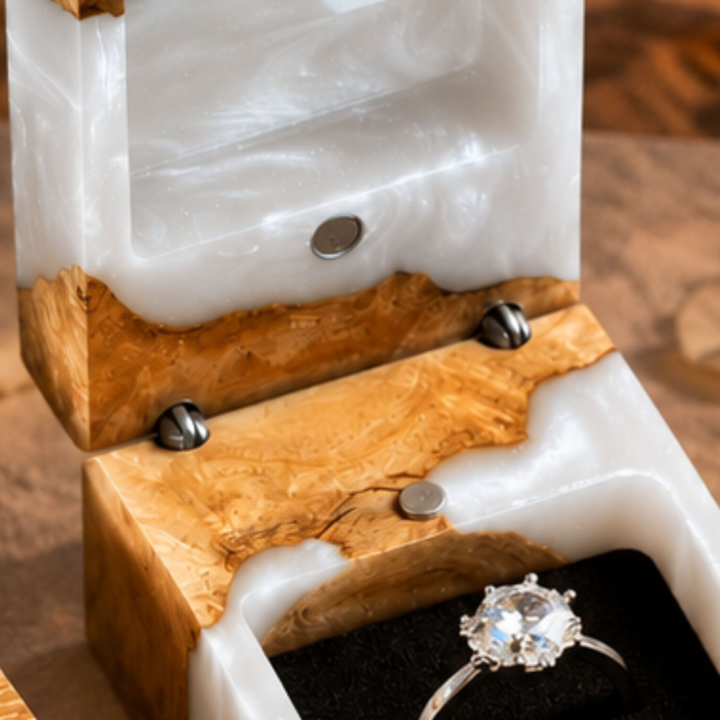 Close-up view of the interior magnetic hinges and velvet ring slot of an open pearl white resin ring box with a diamond ring.