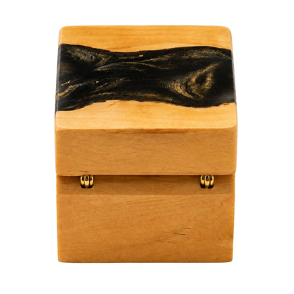 Back view of a wooden ring box featuring gold hinges and a black resin river design across the top lid.