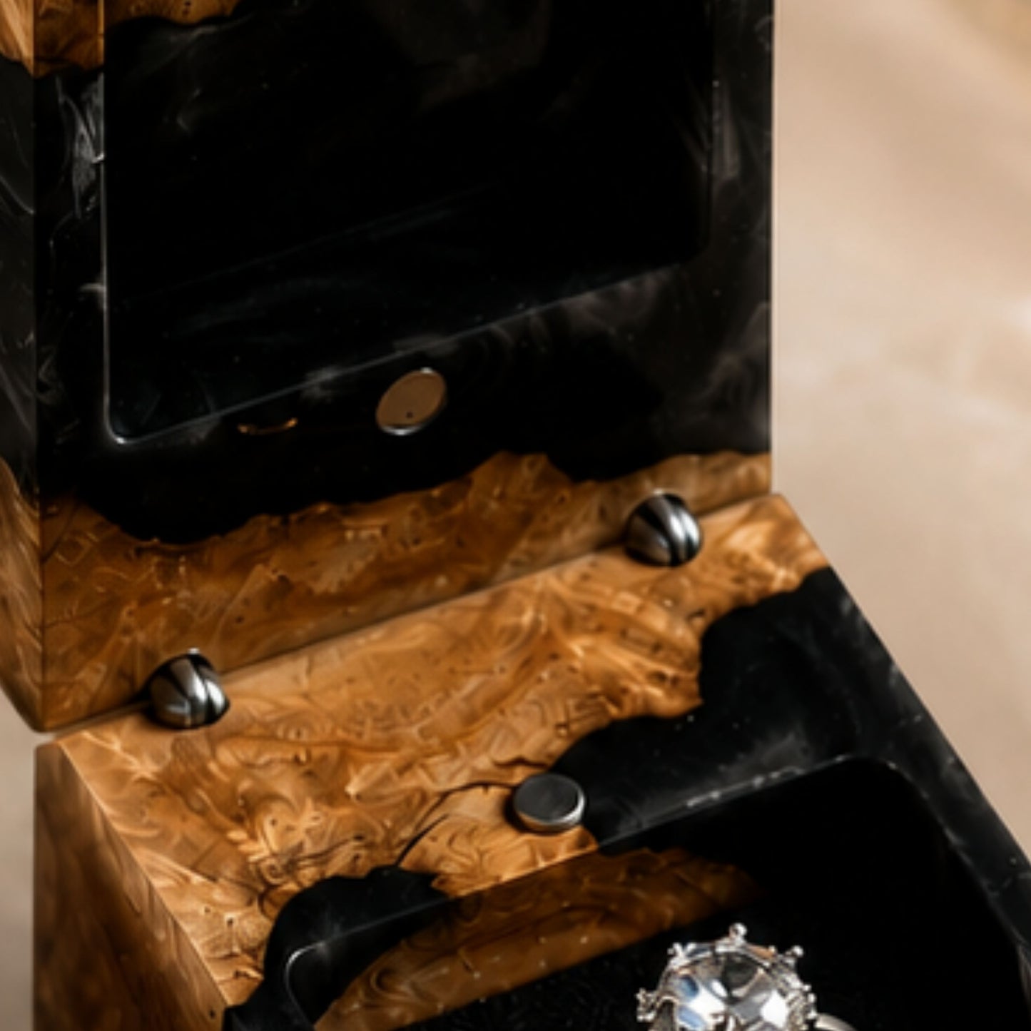 Close-up view of the interior magnetic hinges and velvet ring slot of an open black resin ring box holding a diamond ring.