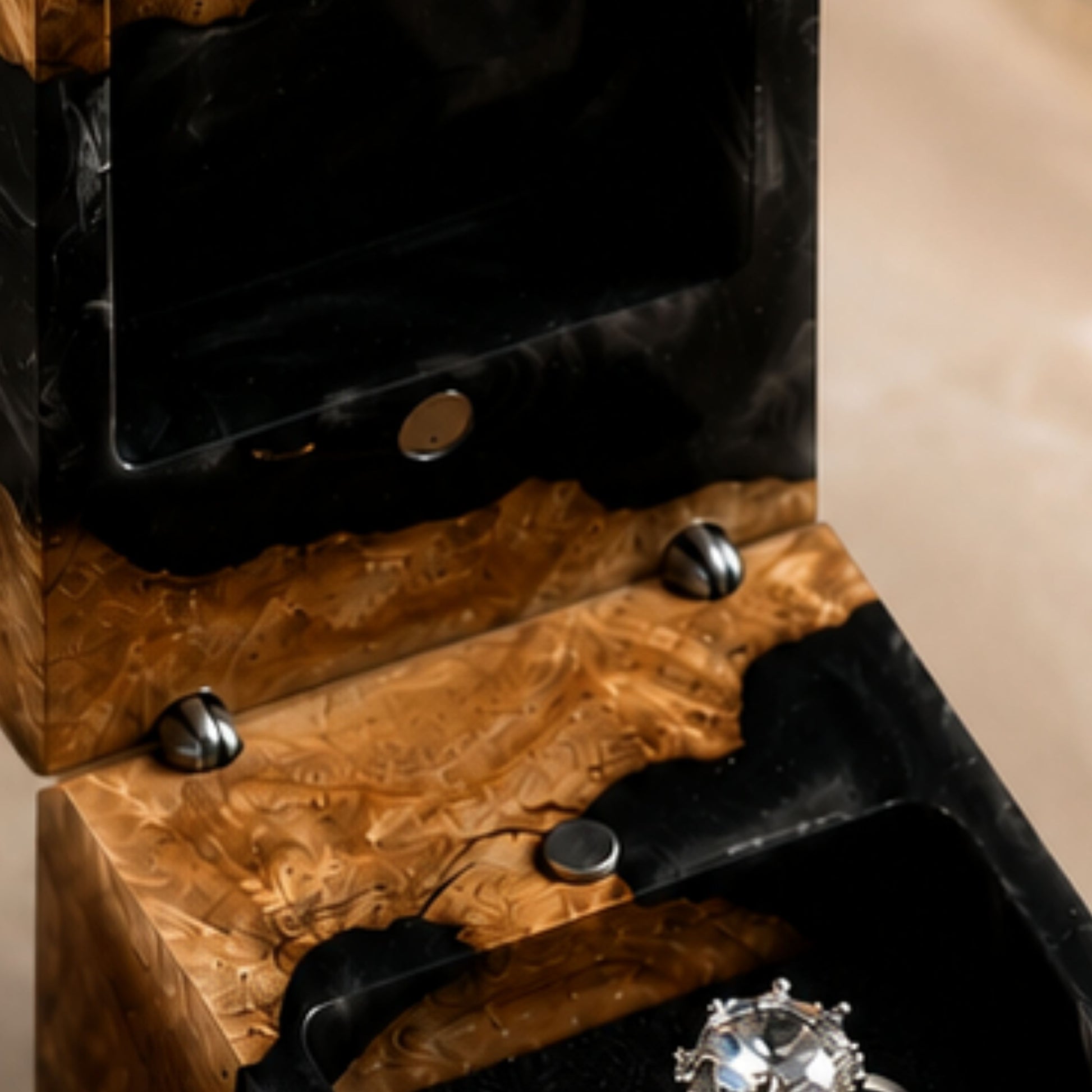 Close-up view of the interior magnetic hinges and velvet ring slot of an open black resin ring box holding a diamond ring.