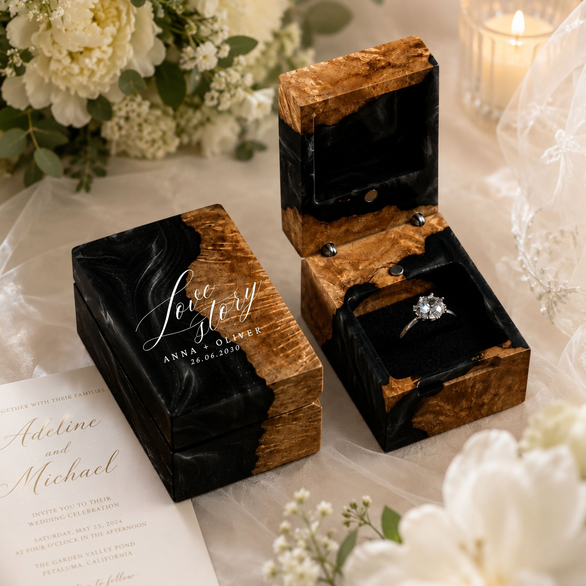 Personalized black resin and wood ring box engraved with couple names and date set in a romantic wedding proposal scene with flowers and invitations.
