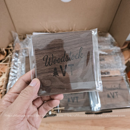 Wooden coaster with 'Woodstock VT' engraving held in front of a cardboard box.