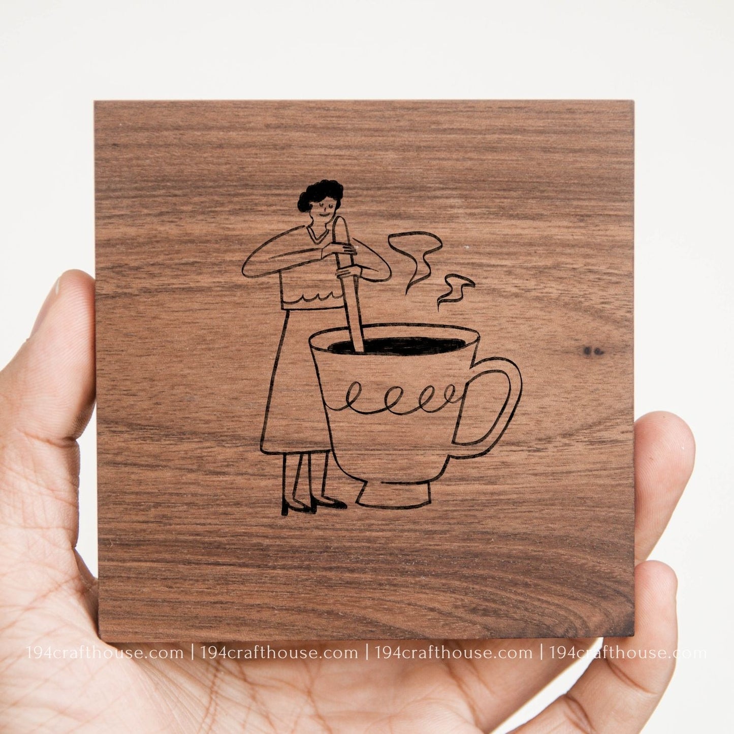 Coffee-making illustration engraved on a handcrafted square walnut wood coaster held in hand