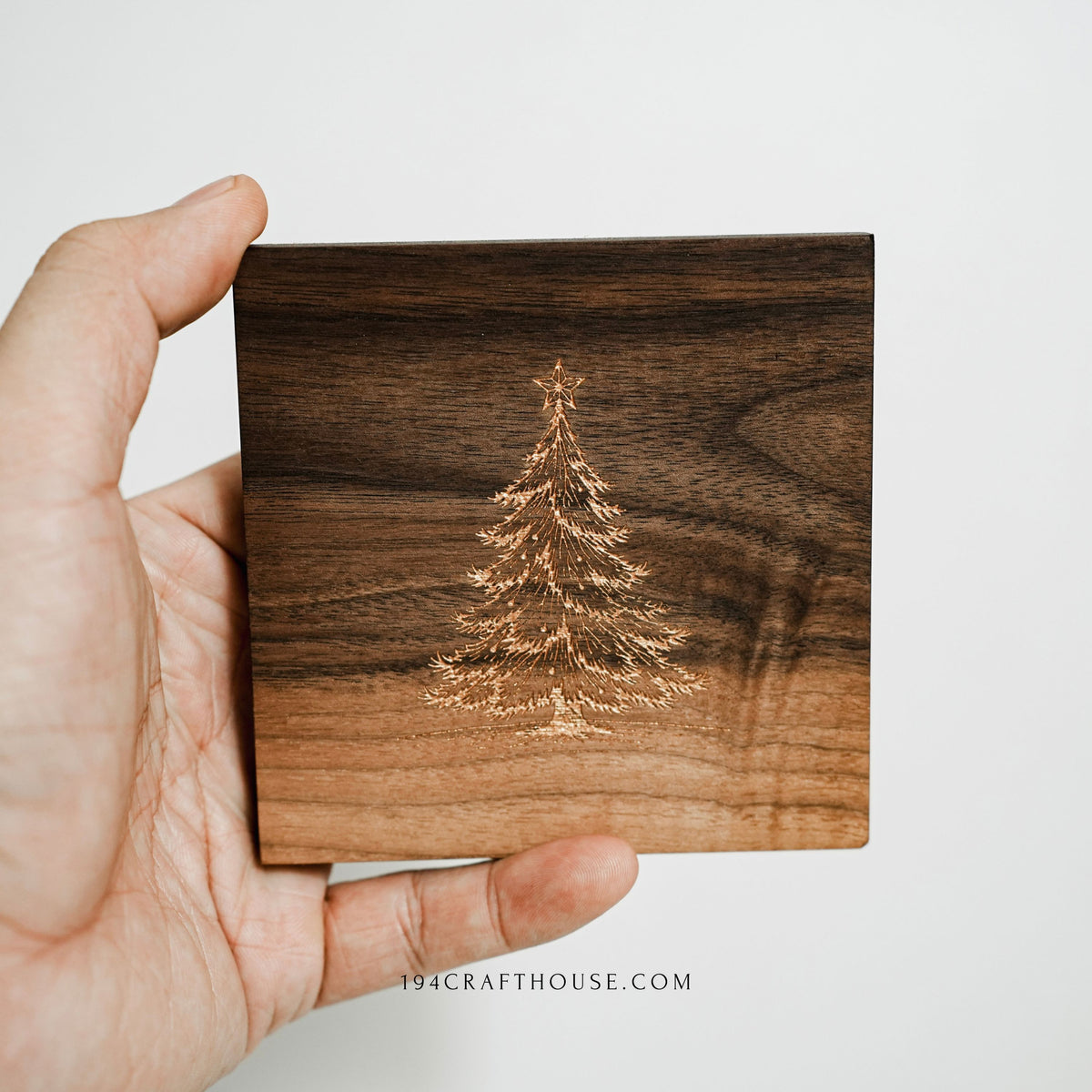 Square walnut coaster showing gold-painted Christmas tree design in natural wood tone