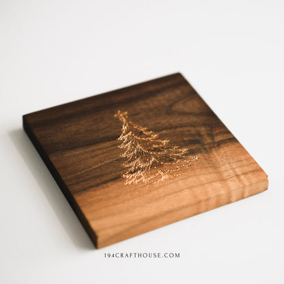 Close view of gold-painted Christmas tree engraving on handmade walnut wood coaster