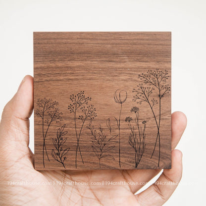 Floral design engraved on a handcrafted square walnut wood coaster with natural wood grain