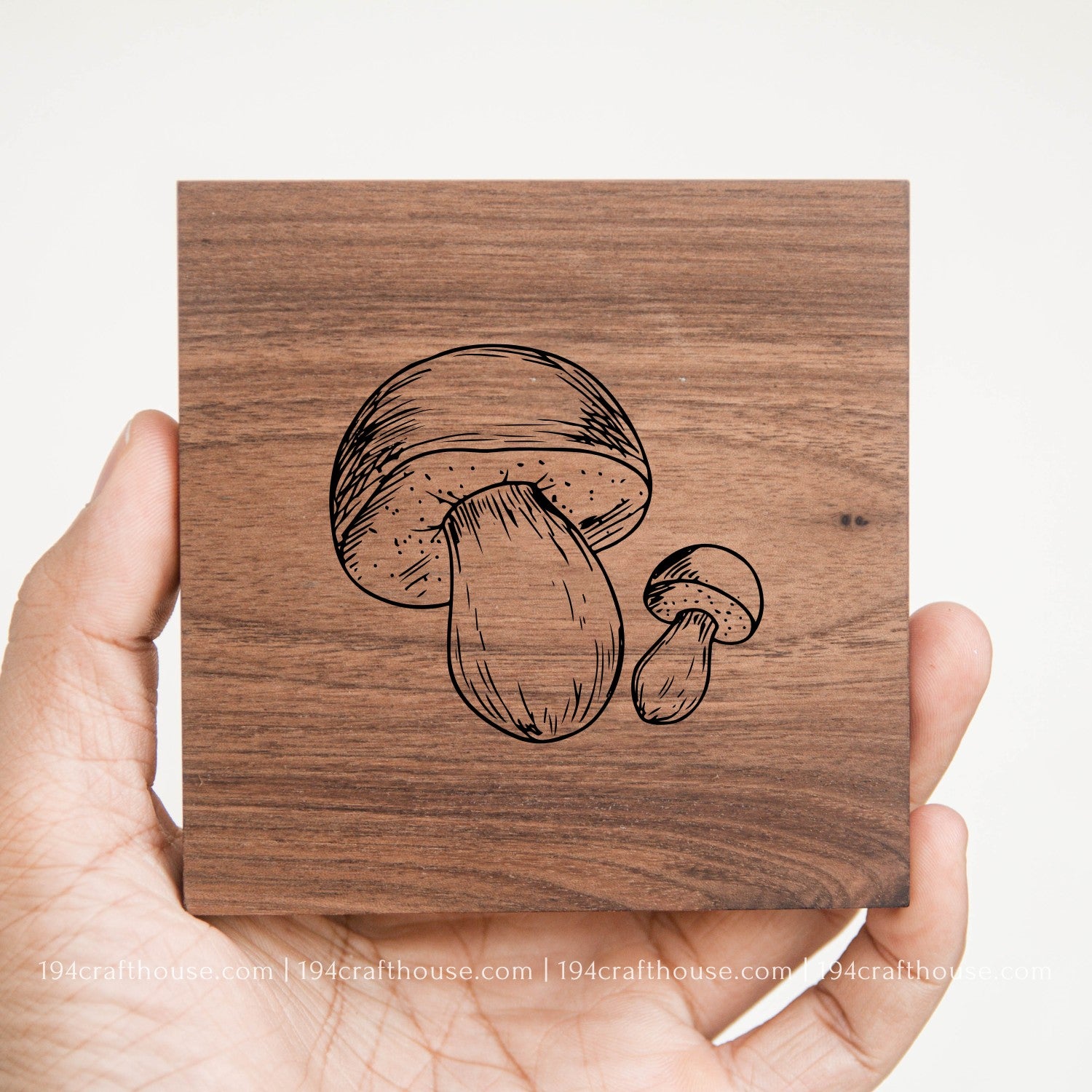 Mushroom design engraved on a handcrafted square walnut wood coaster held in hand