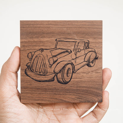 Wooden coaster with engraved vintage car design held by a hand on a white background
