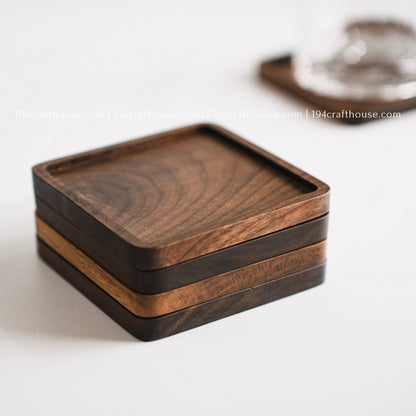 Top-down view of  a set of 4 square hand-carved walnut wood coasters with smooth rounded corners on a clean white surface by 194 Craft House