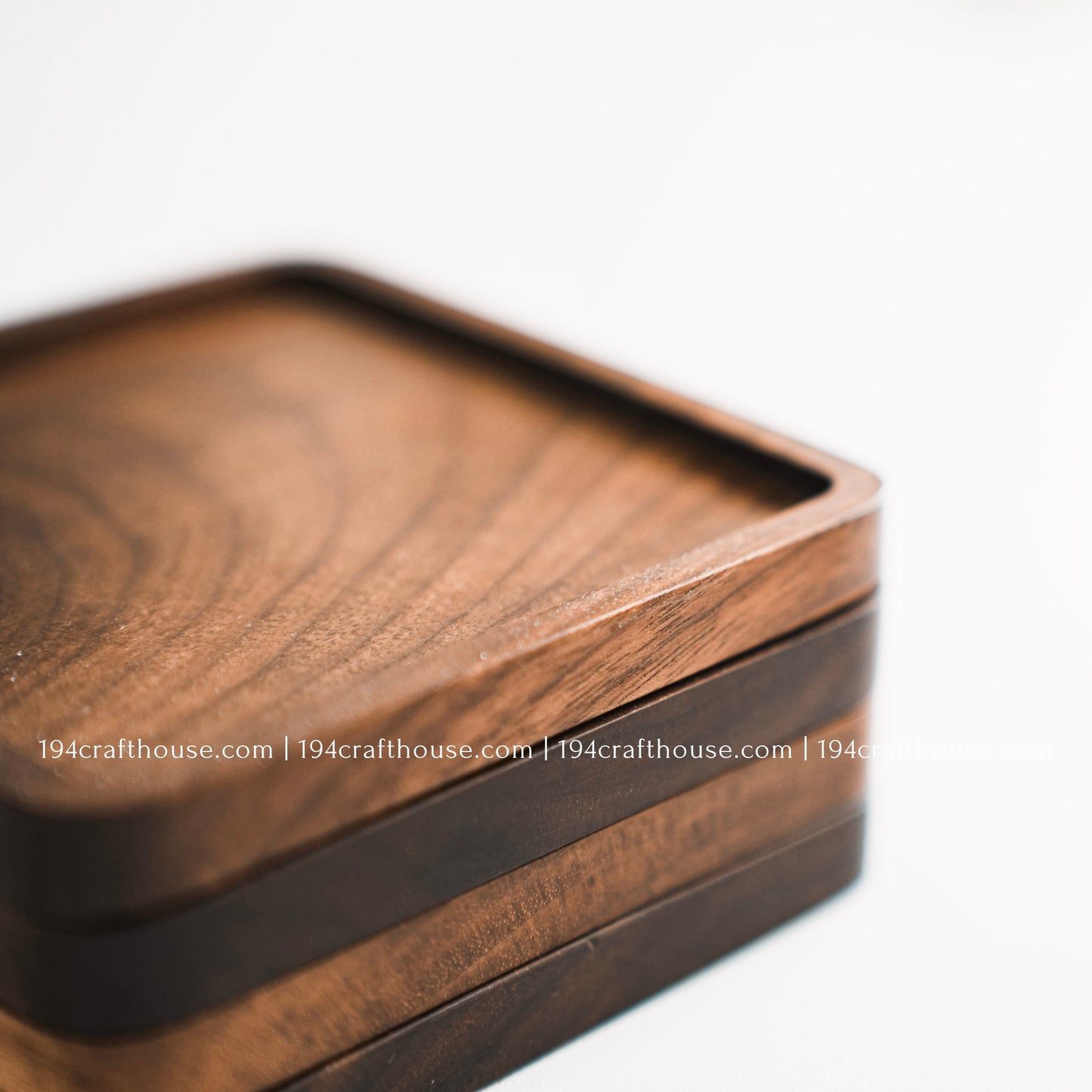 Top-down view of a set of 4 square hand-carved walnut wood coasters with smooth rounded corners on a clean white surface by 194 Craft House