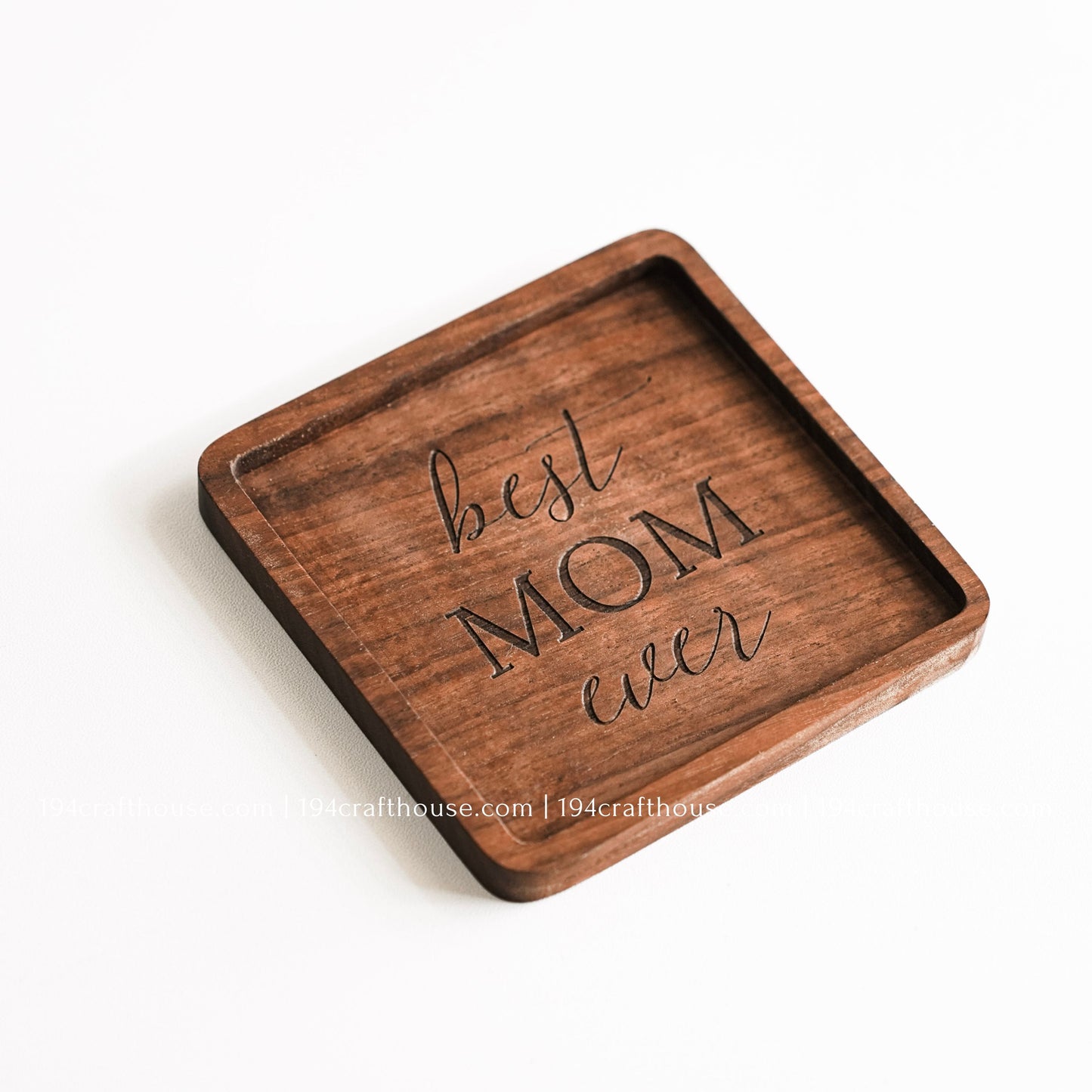 Top-down view of a Best Mom Ever engraved on a single square hand-carved walnut wood coaster with smooth rounded corners on a clean white surface by 194 Craft House