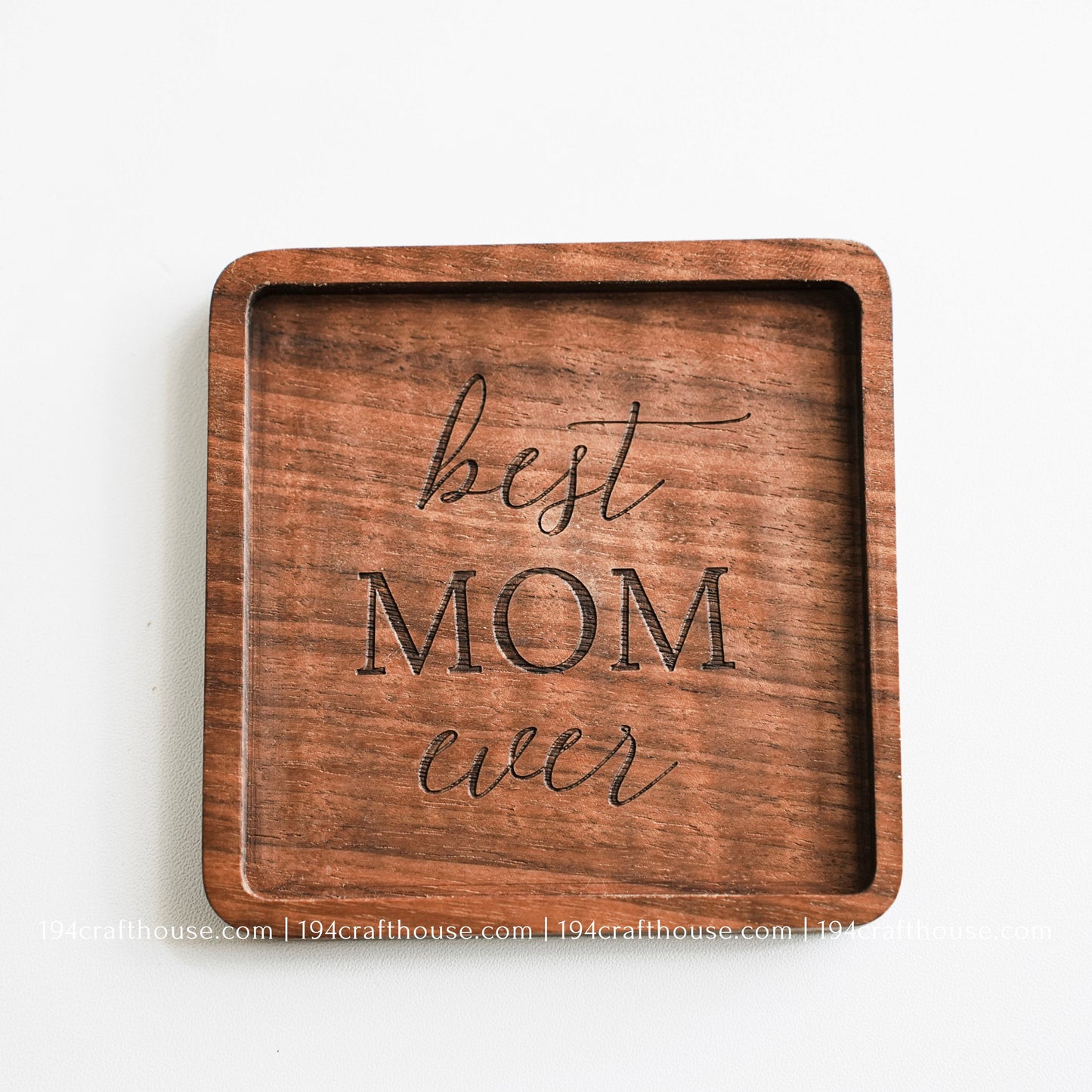 Top-down view of a glass stand on a Best Mom Ever engraved on a single square hand-carved walnut wood coaster with smooth rounded corners on a clean white surface by 194 Craft House