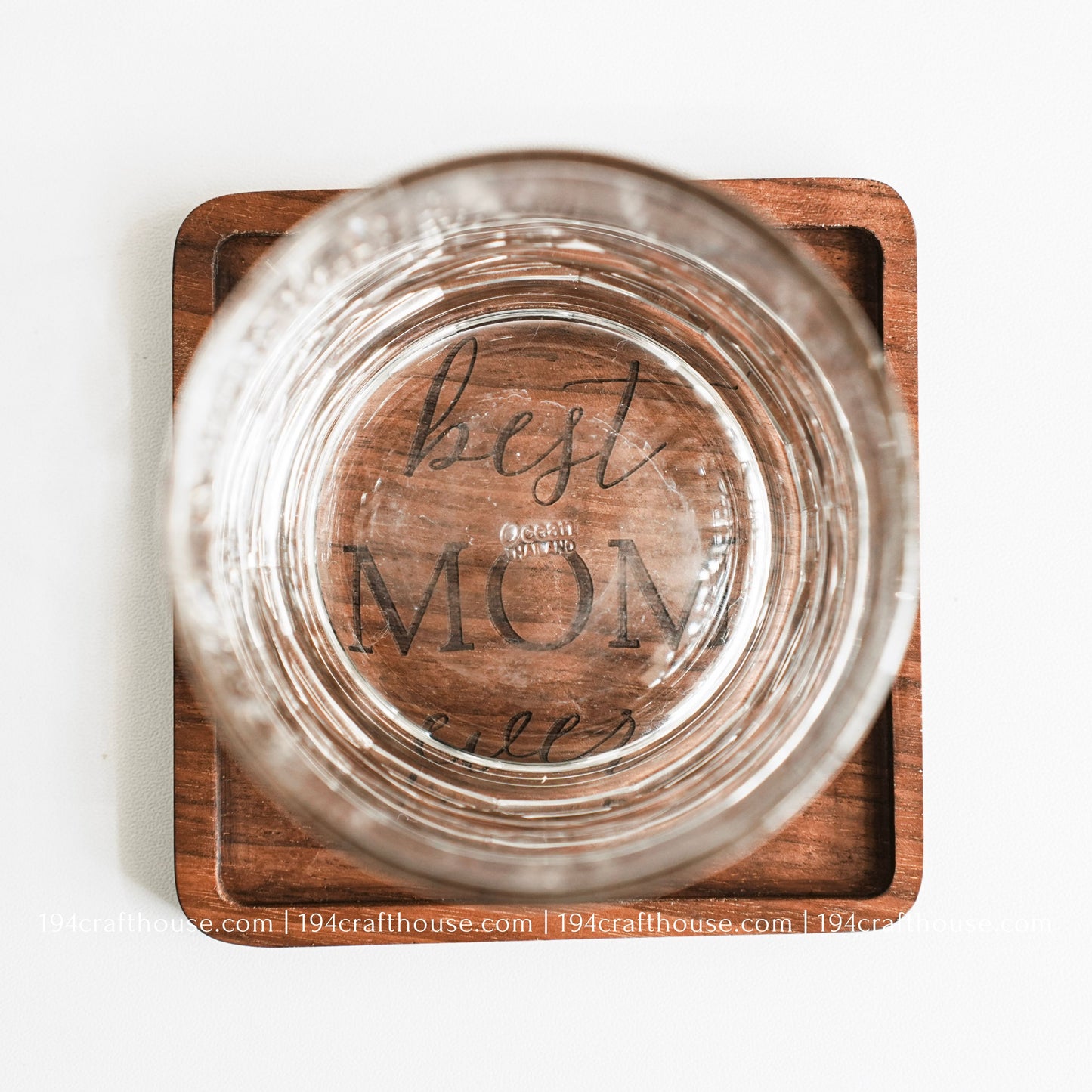 Top-down view of a glass stand on a Best Mom Ever engraved on a single square hand-carved walnut wood coaster with smooth rounded corners on a clean white surface by 194 Craft House