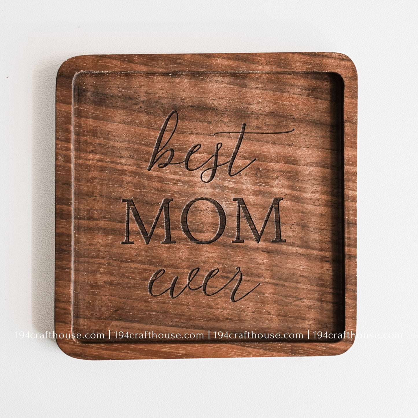 Top-down view of a Best Mom Ever engraved on a single square hand-carved walnut wood coaster with smooth rounded corners on a clean white surface by 194 Craft House
