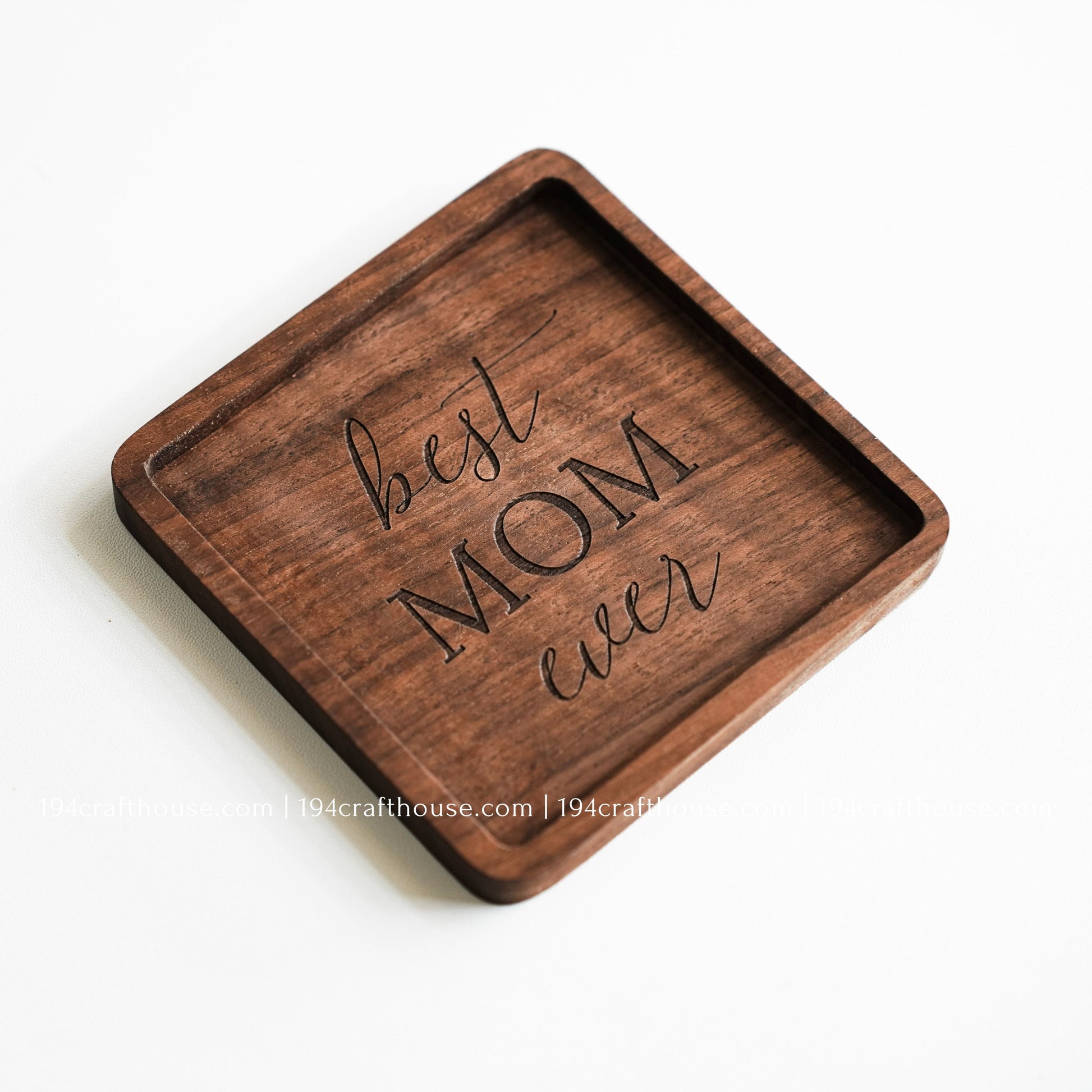 Top-down view of a Best Mom Ever engraved on a single square hand-carved walnut wood coaster with smooth rounded corners on a clean white surface by 194 Craft House