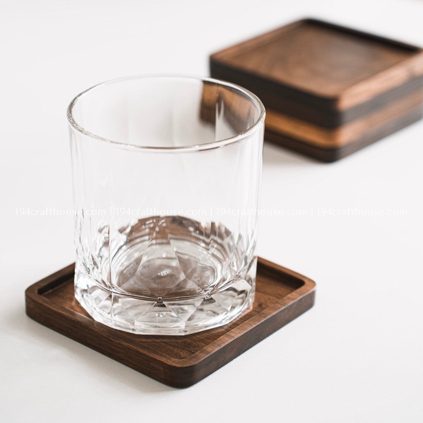 Drinking glass placed on a square walnut wood coaster for coffee table and dining table use