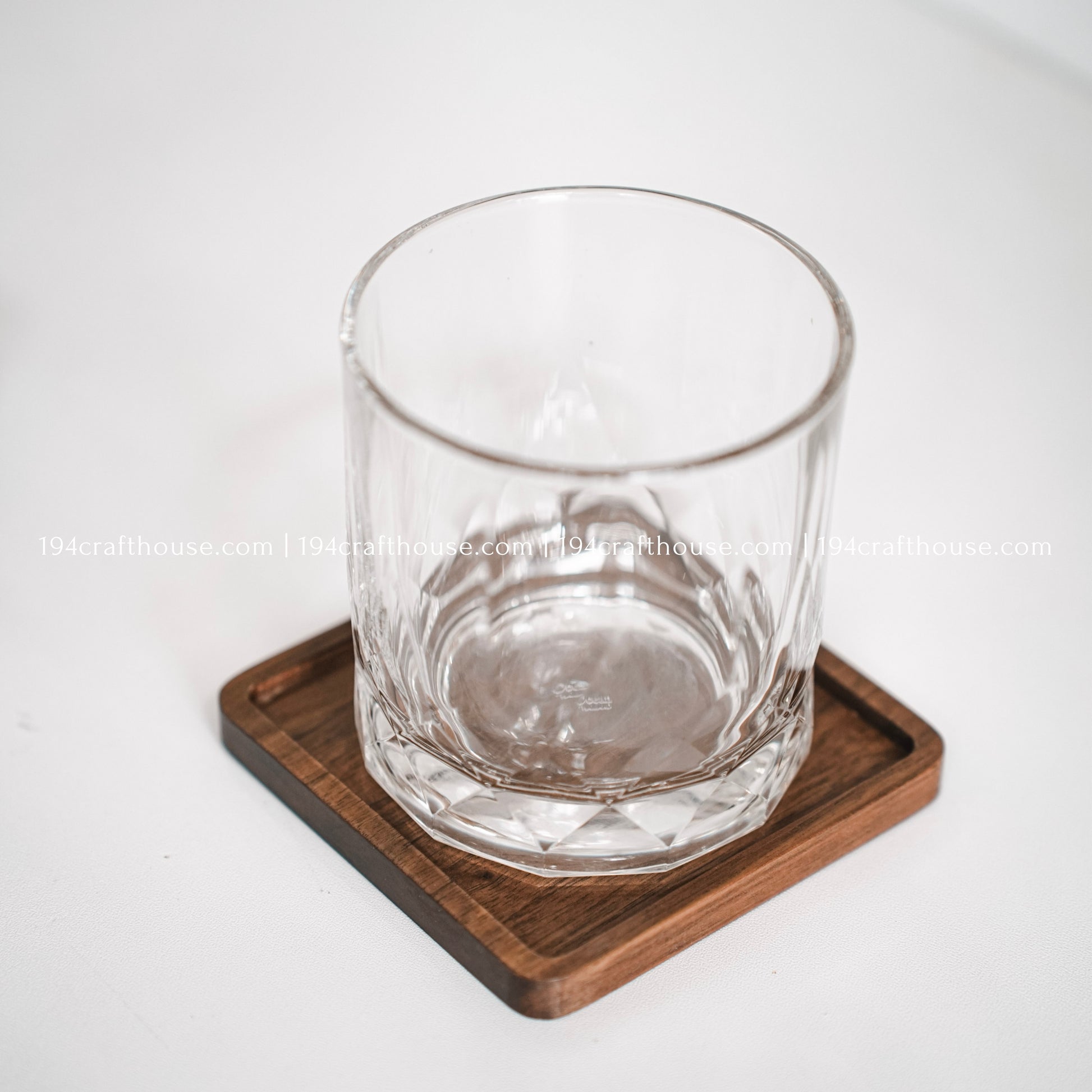 Top-down view of a glass stand on a single square hand-carved walnut wood coaster with smooth rounded corners on a clean white surface by 194 Craft House