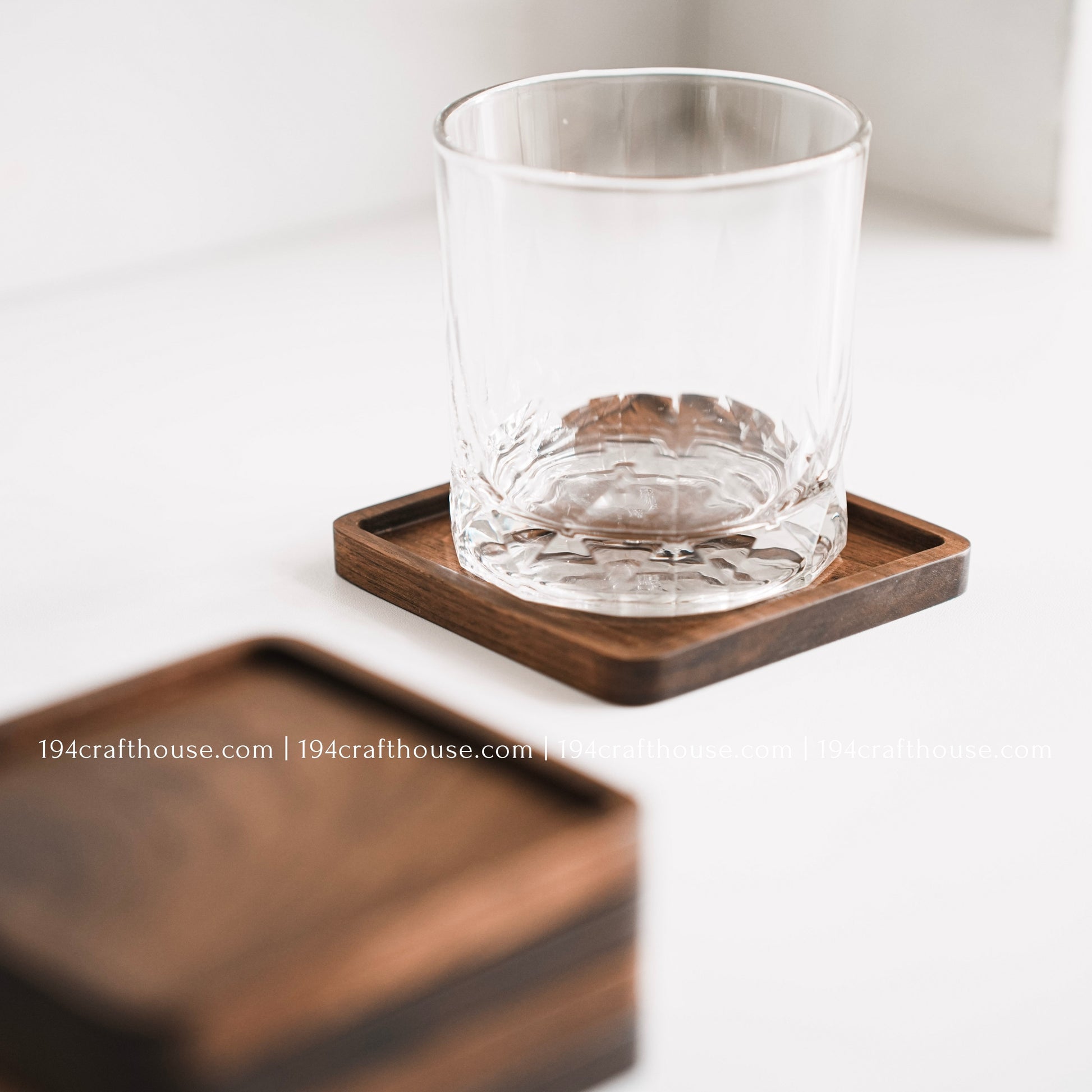 Top-down view of a glass stand on a single square hand-carved walnut wood coaster with smooth rounded corners on a clean white surface by 194 Craft House