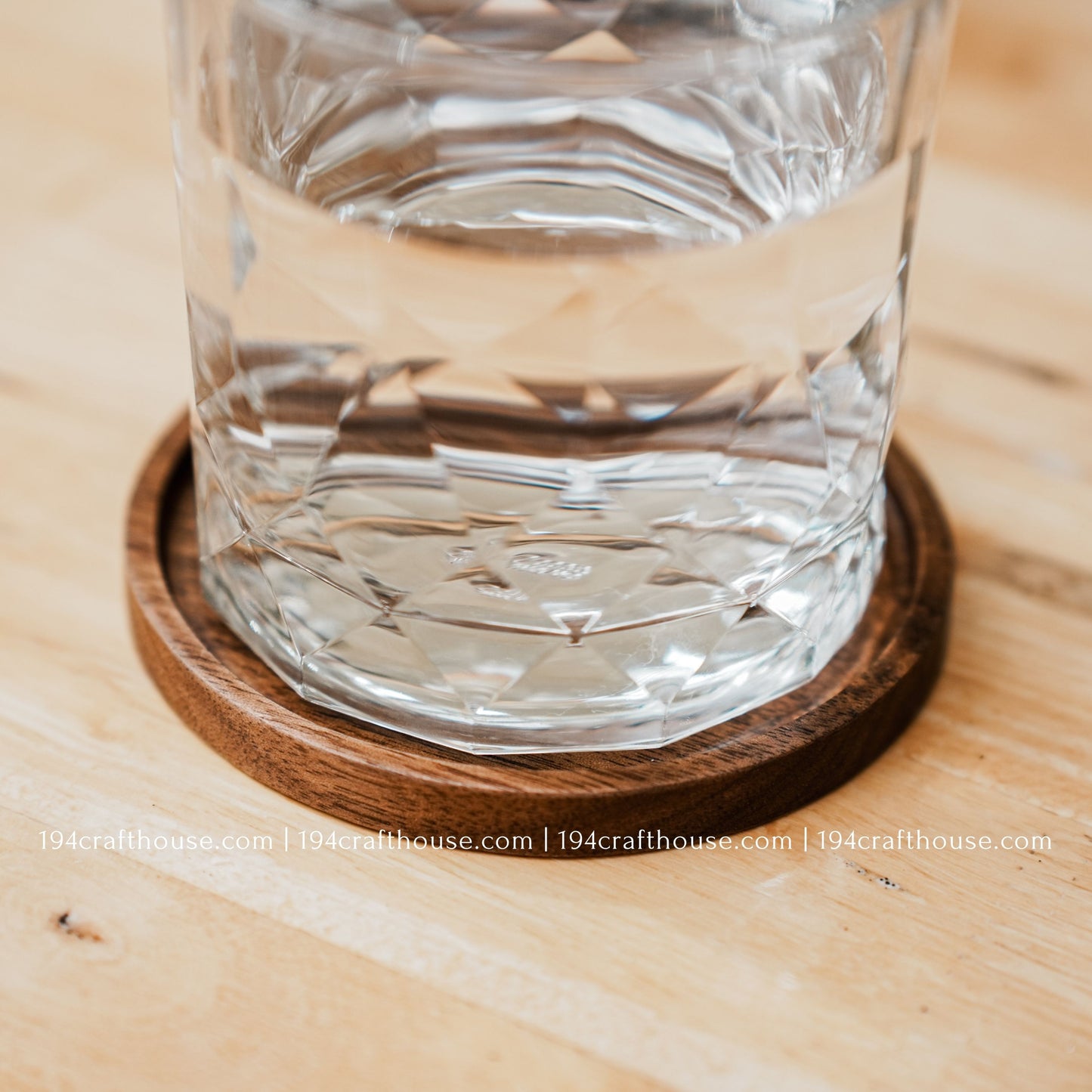 A glass stand on the single round hand-carved walnut wood coaster by 194 Craft House