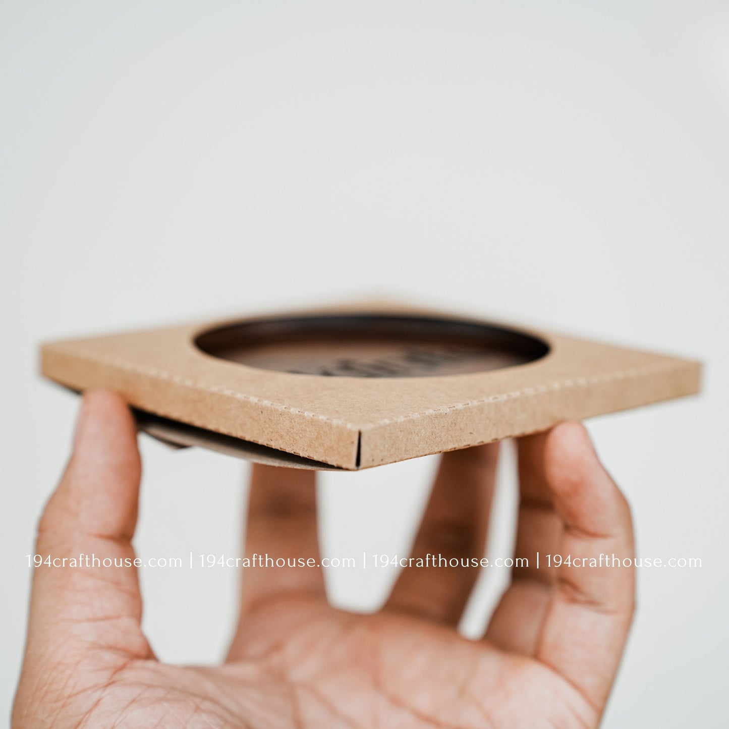 A single round hand-carved walnut wood coaster on hand with a carton cover by 194 Craft House