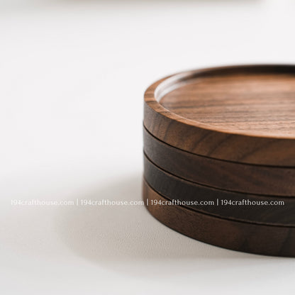 Top-down view of a set of 4 round hand-carved walnut wood coaster with smooth rounded corners on a clean white surface by 194 Craft House