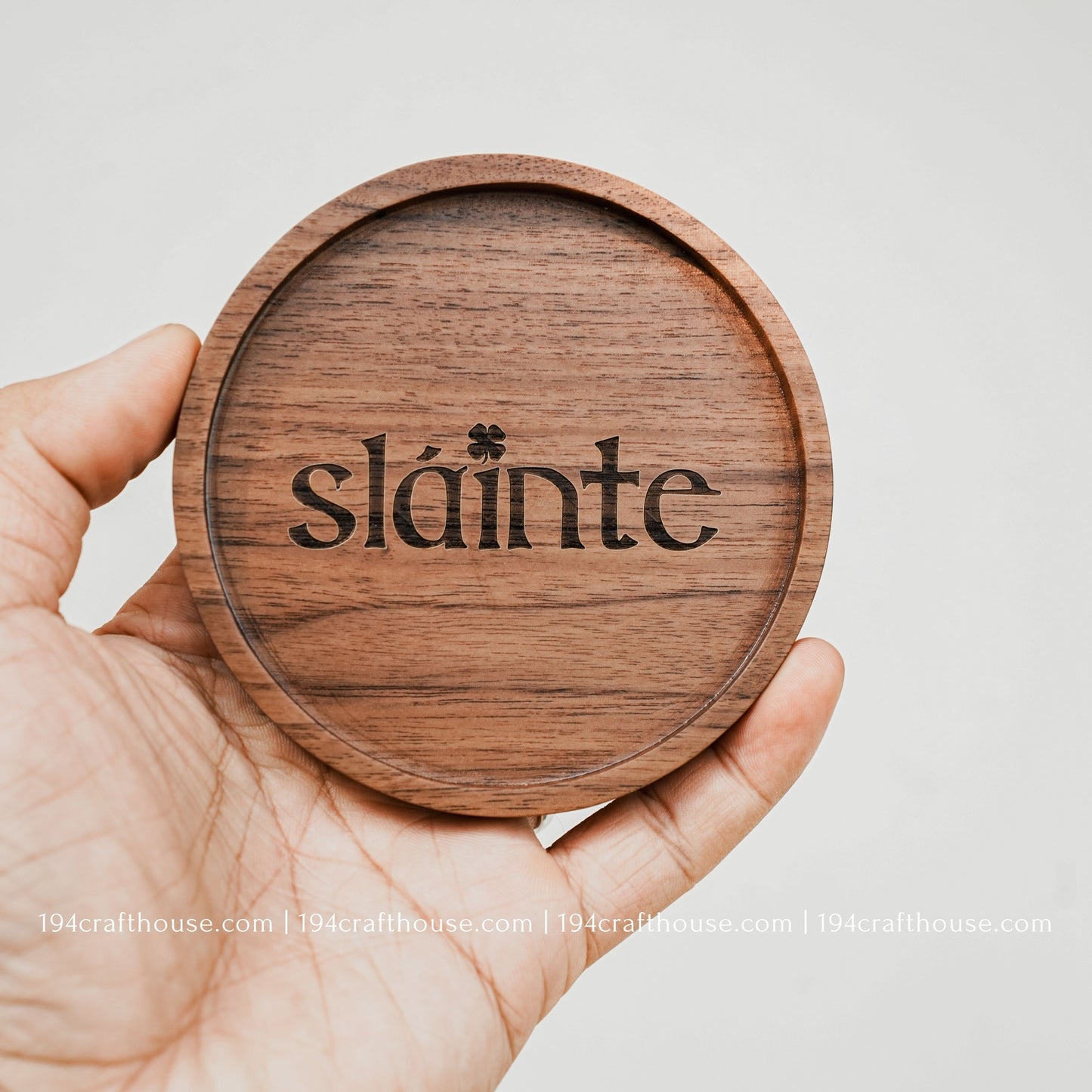 A single round hand-carved walnut wood coaster on hand with engraving text Slainte by 194 Craft House