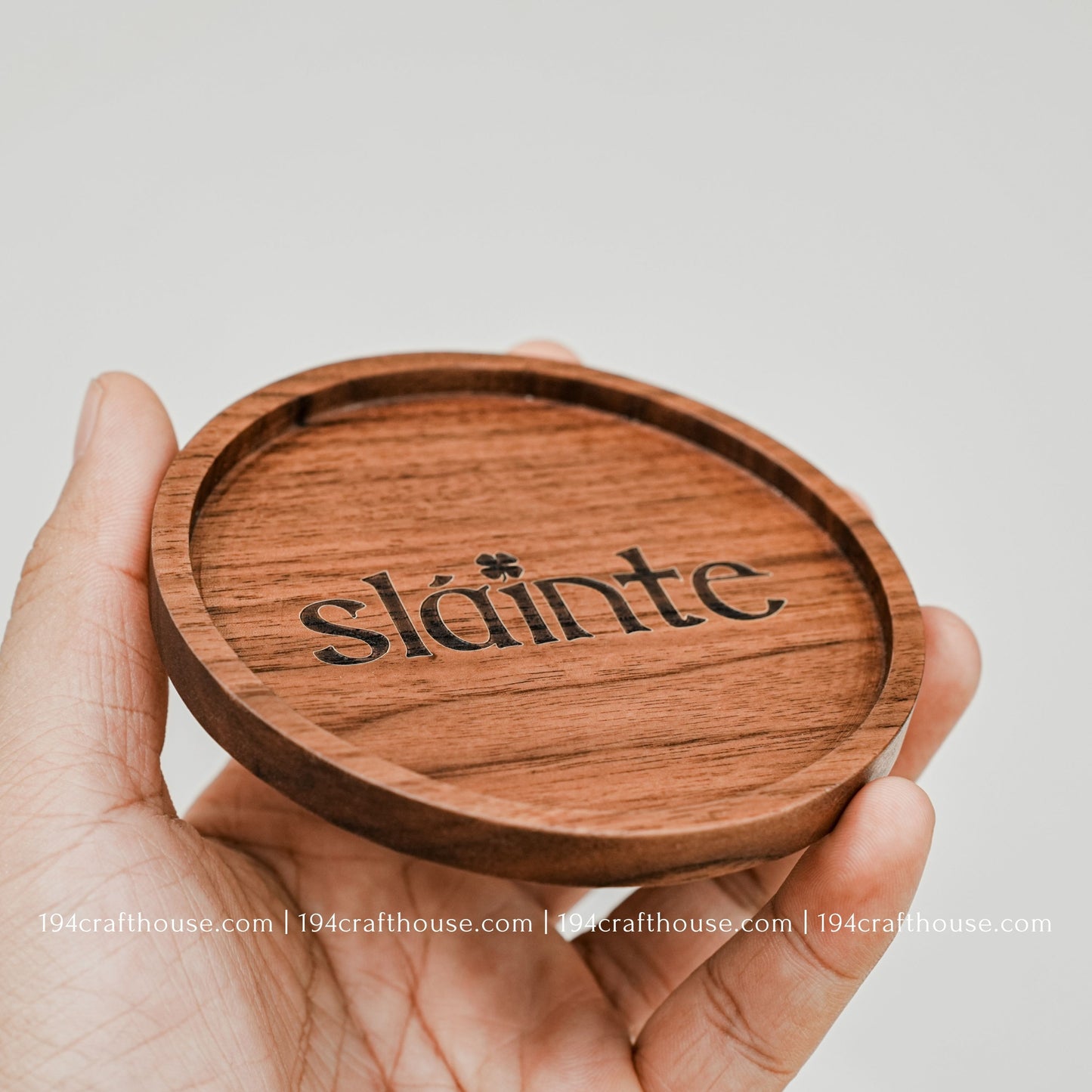 A single round hand-carved walnut wood coaster on hand with engraving text Slainte by 194 Craft House