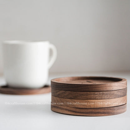 Stacked round walnut wood coasters shown from the side to highlight their thickness and natural grain