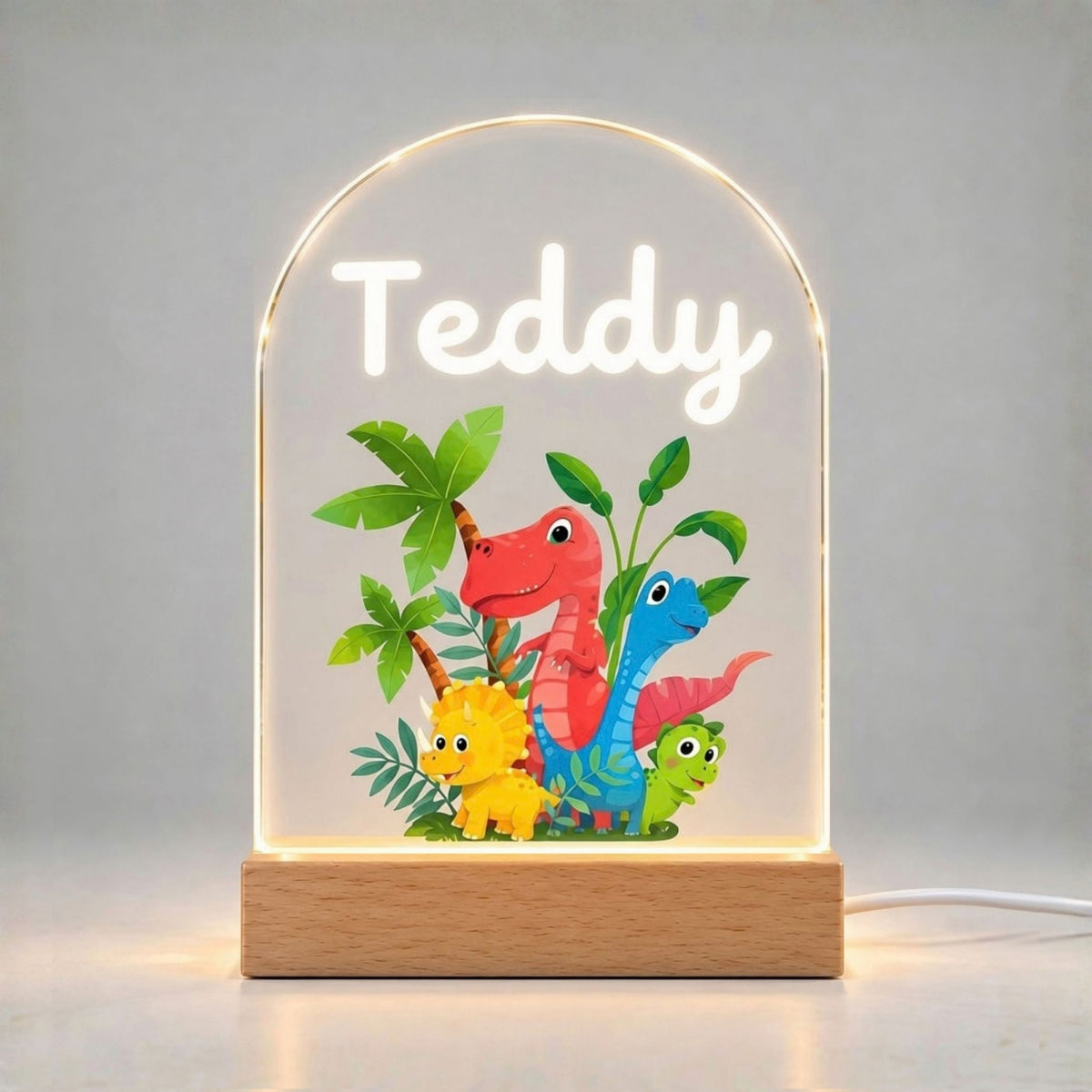 Illuminated arched panel displays the name Teddy above a colorful group of dinosaurs