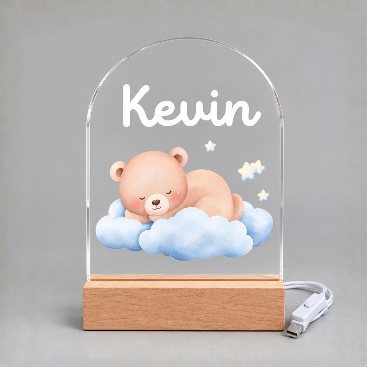 Unlit arched acrylic panel shows Kevin, a sleeping bear, blue clouds, and stars above a wood-tone base.