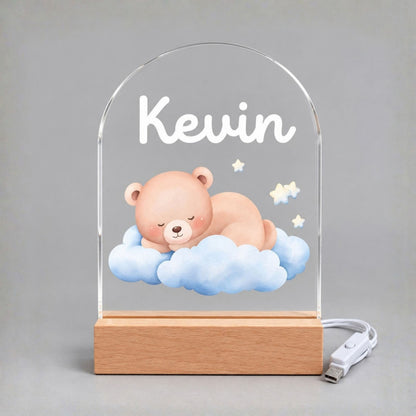 Unlit arched acrylic panel shows Kevin, a sleeping bear, blue clouds, and stars above a wood-tone base.
